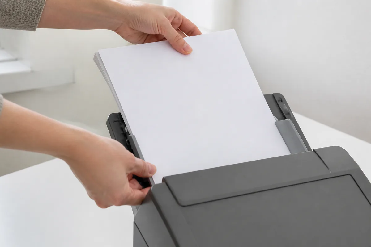 Mains plaçant des documents dans un scanner de bureau pour numérisation