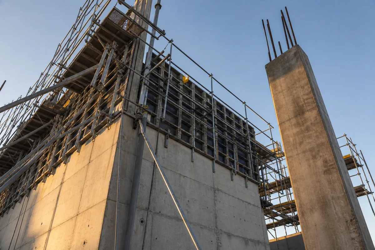 Chantier de gros œuvre au petit matin, banches de coffrage et échafaudage en contre-plongée